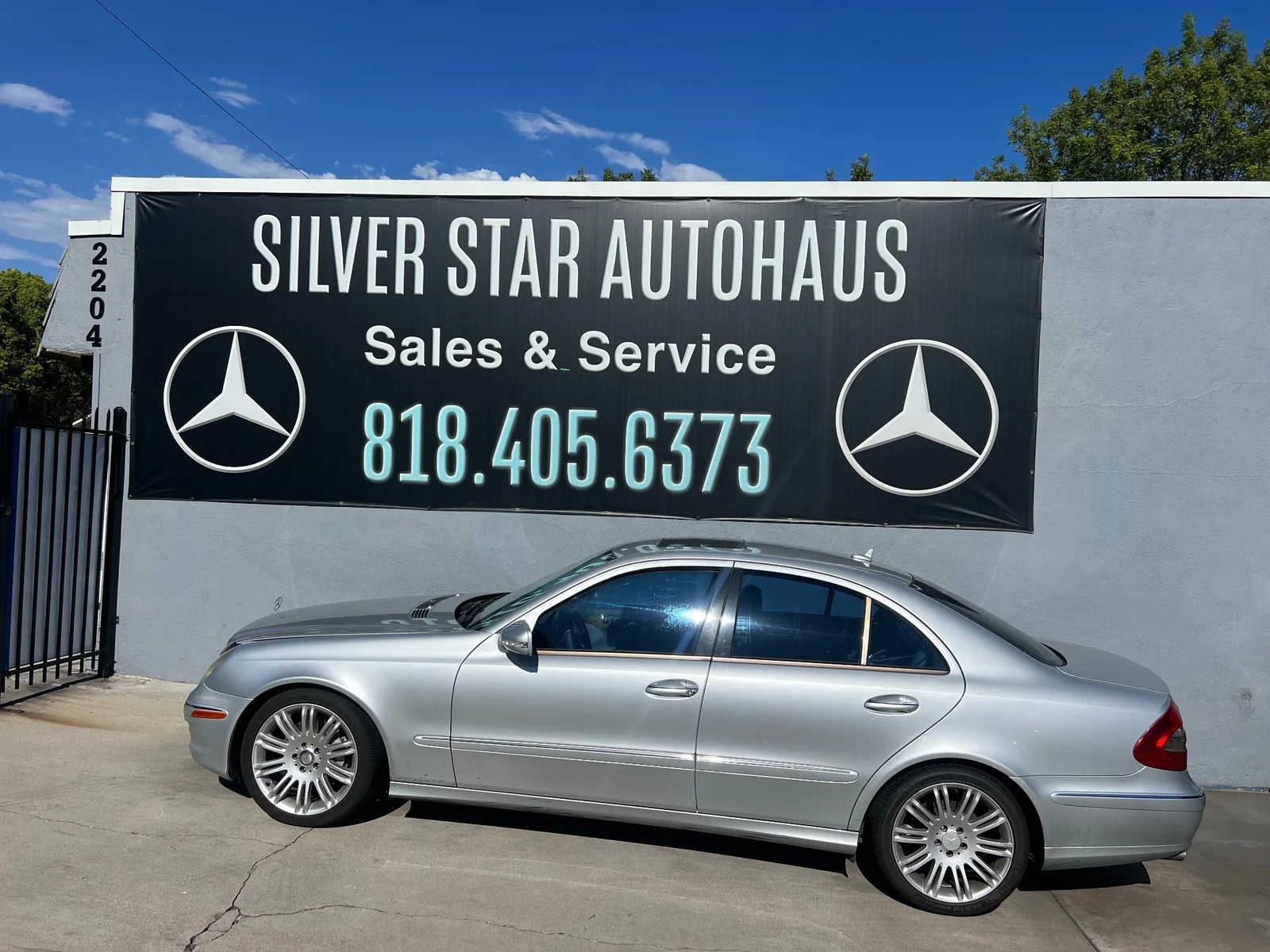 Silver Mercedes-Benz sedan parked in front of the Silver Star Autohaus Sales and Service sign